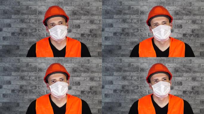 灰色砖墙背景上戴着医用面具的年轻人的肖像。成年男性用口罩遮住脸，保护自己免受疾病侵害。冠状病毒流行病