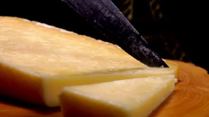 刀的特写镜头正在木板上切割法国硬奶酪