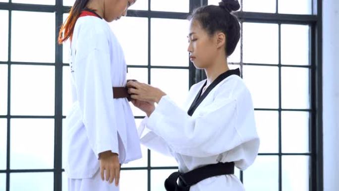教练帮助女孩调整跆拳道的训练服装