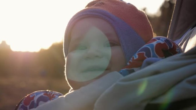 美丽微笑的小婴儿在夕阳下散步时穿着暖和的衣服的肖像