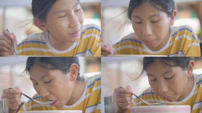 亚洲女孩在餐厅喝米汤。