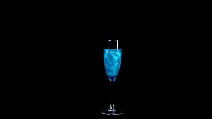 蓝色液体玻璃。长生不老药旋转并溢出液体。爱情的药水被隔离在黑色背景上。