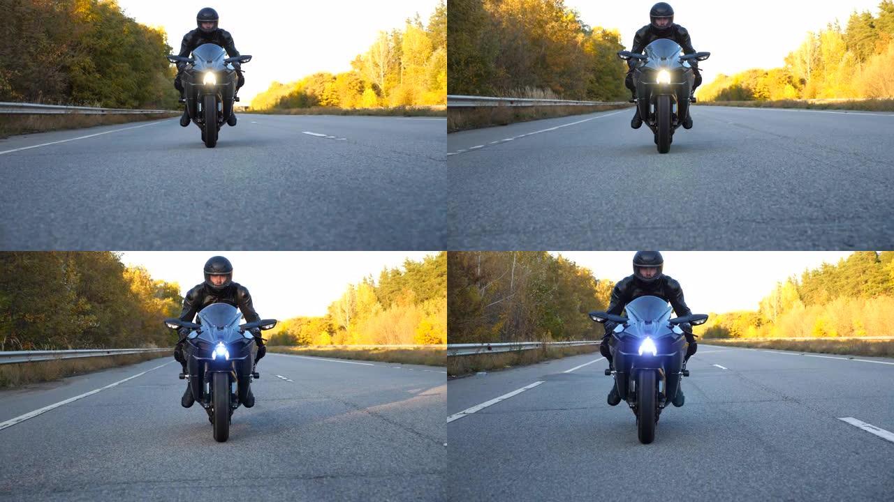 摩托车手在乡间小路上骑摩托车。戴着头盔的年轻人在高速公路上快速骑现代运动摩托车。旅途中开车的人。冒险