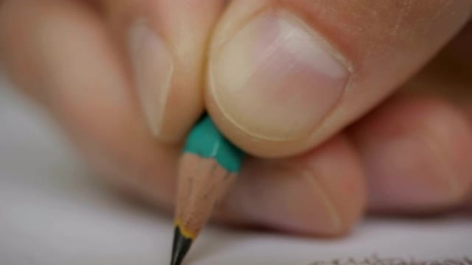 艺术家手画木铅笔在纸上写字。极端特写超级微距拍摄的一个男人的手写的东西在纸笔笔记本铅笔。特写。UHD