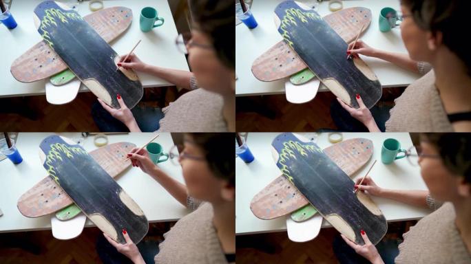 年轻的女艺术家在滑板板上画画