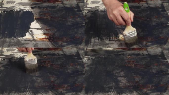 抽象画黑色在木质背景上，死在垃圾风格上，深色画在胶合板上，男人的手用刷子或滚筒