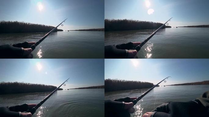 在阳光明媚的天气里，垂钓者在美丽的河上的旋转竿上钓鱼，第一人称视角