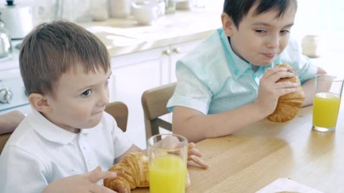 两个男婴在厨房吃羊角面包