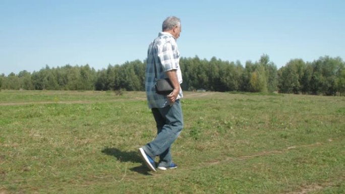 穿着牛仔裤的活跃养老金领取者积极沿着绿色草坪行走
