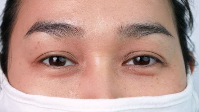 在白色背景上，戴着口罩的亚洲妇女的特写脸，以防止空气污染或病毒流行。医疗保健概念。