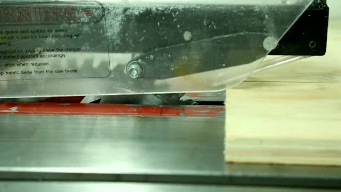 在切割木板的机器上工作的男人的手的特写