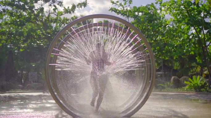 一名年轻女子在水上公园 (aqua park) 穿过圆形按摩淋浴。慢动作镜头