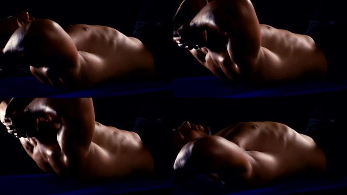 英俊强壮的健美运动员在黑色背景健美概念的地板上做腹肌锻炼仰卧起坐，4k