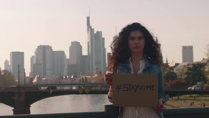 德国法兰克福，2020年4月8日年轻女性对抗科罗纳，病毒在天际线前举着 # stayhome的牌子