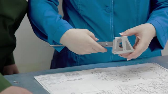 女工程师正在使用游标卡尺来检查数控机床上制造的产品的尺寸。车间的金属零件。行业概念。工厂的高精度设备