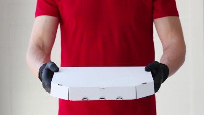 戴着橡胶手套的男性双手用纸板披萨caroboca伸出双手。在冠状病毒大流行检疫期间运送食物。送货上门