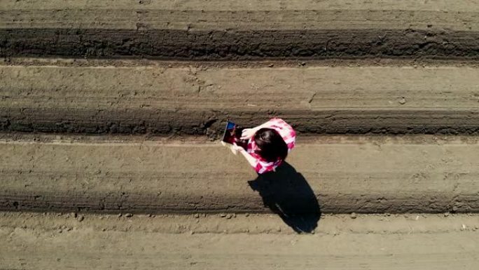 航空。女农民、农学家以特殊的土壤行在田间。她用药片测试拖拉机自动种植土豆的质量。现代农业,农业。春天