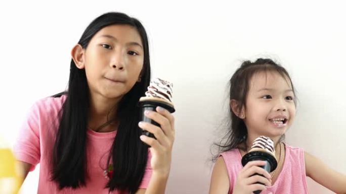 亚洲孩子在家和姐姐一起吃冰淇淋蛋卷，慢动作。