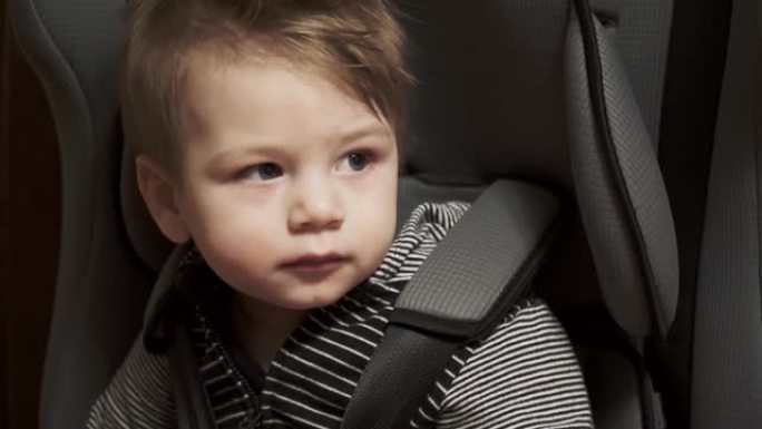 男婴坐在汽车上的儿童座椅上