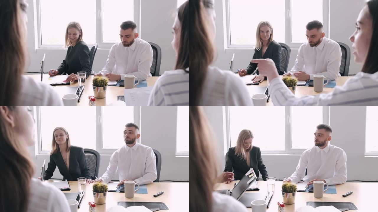 男男女女坐在办公室的桌子旁，听他们的同事说话
