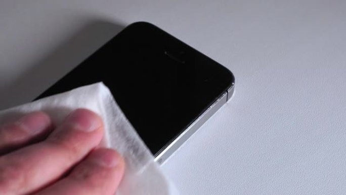男子用酒精或消毒剂清洁智能手机屏幕。清洗脏屏幕手机的概念，防止细菌感染。消毒预防冠状病毒