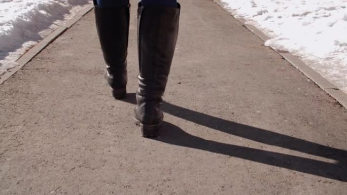 穿着靴子走在柏油路上的女人的短视