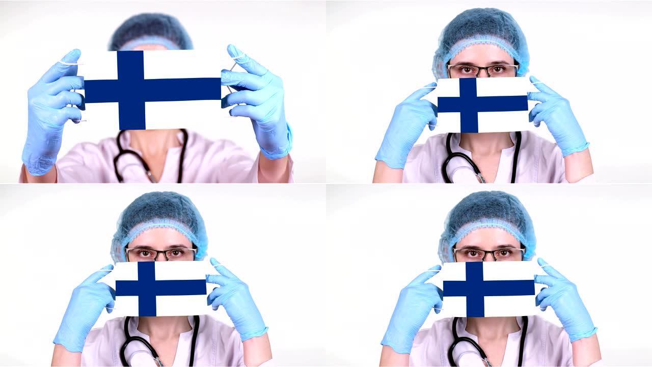 特写。戴眼镜的医生，蓝色医疗帽，手套手持带有芬兰国旗的医用口罩。医生护理，冠状病毒期间国家保护，全球