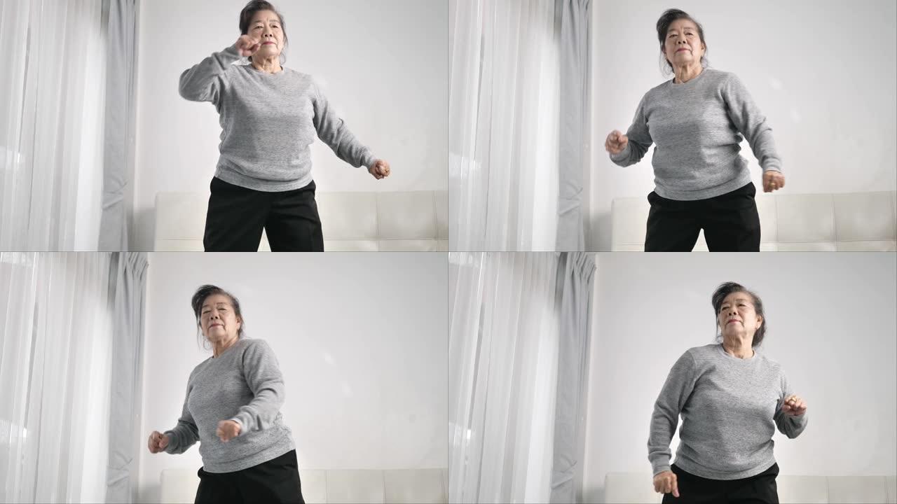 亚洲老年妇女在家里锻炼和跳舞，呆在家里的生活方式概念。缓慢的运动。