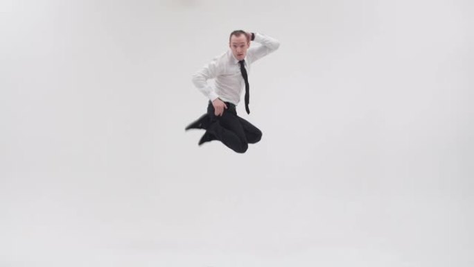 Breakdancer展示了霹雳舞的动作，跳开双腿，穿着白色背景的领带穿着办公室衣服。成年男性霹雳舞