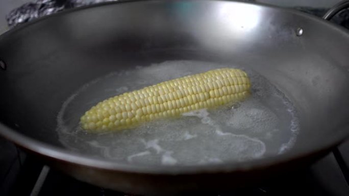 在厨房里用沸水煮玉米。