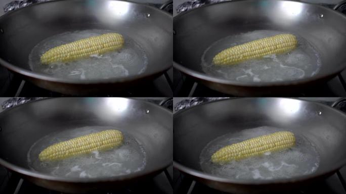 在厨房里用沸水煮玉米。