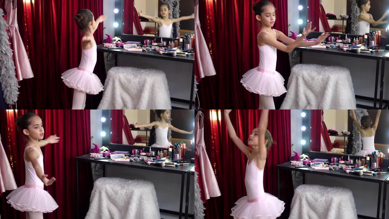 4k快乐美丽的小芭蕾舞女舞者穿着粉色芭蕾舞裙在更衣室的镜子前练习舞蹈。微笑可爱的女孩享受在化妆室跳舞