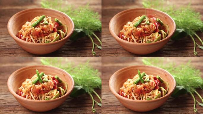 Som Tam是受欢迎的泰国菜。木瓜沙拉配干虾、咸蟹、辣椒、番茄和辛辣香草。配蔬菜。静静在工作室拍摄