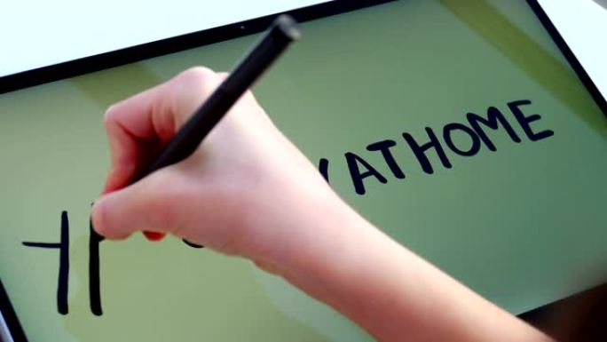 特写，孩子们的手在平板电脑的屏幕上写字，笔记本电脑的标签在家里的碑文书房附近