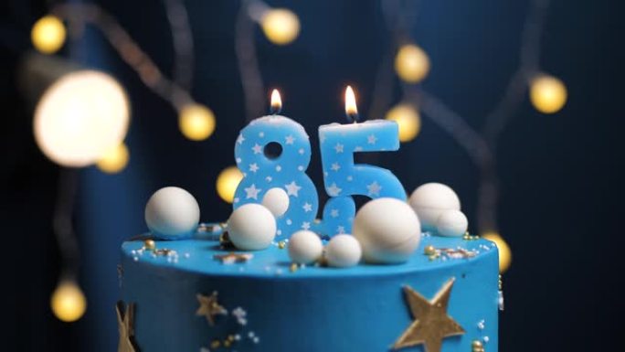生日蛋糕编号85星星天空和月亮概念，蓝色蜡烛被打火机点燃，然后吹灭。如果需要，请在屏幕右侧复制空间。