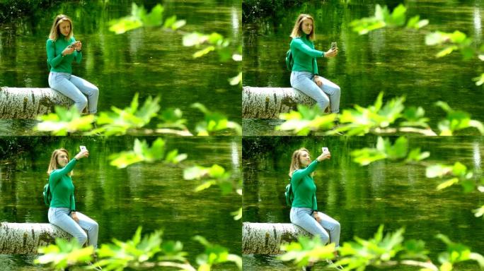 年轻女子在森林河上用智能手机休息