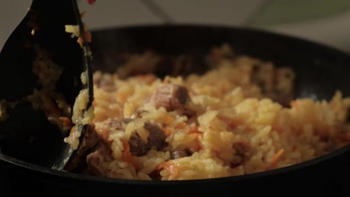 烹饪抓饭特写。慢动作混合一勺米饭。在家自煮