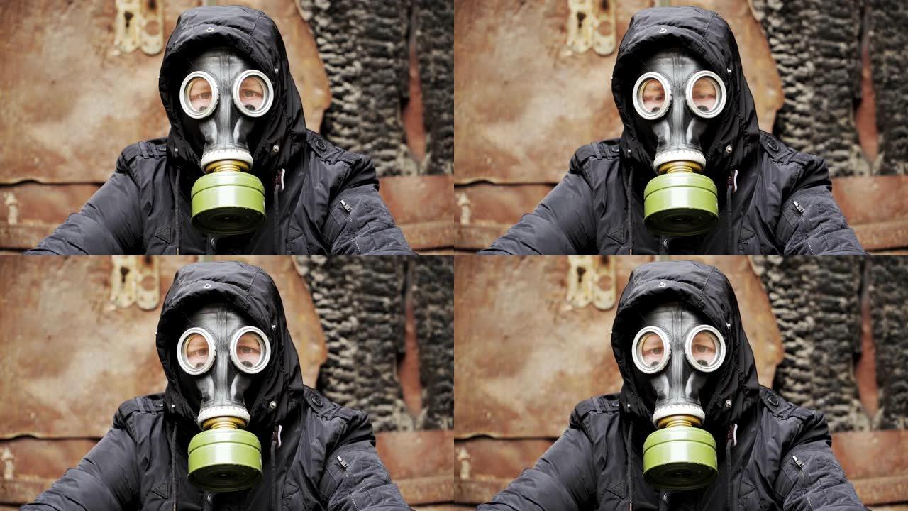 肖像。一个戴着防毒面具穿着黑色连帽衫的人坐在一座废弃建筑的背景上。后启示录世界。跟踪者概念，核化学战