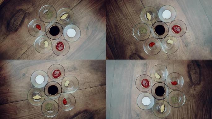 各种类型的香料在玻璃碗上的木制棕色桌子: 盐，大豆酱，番茄酱，姜酱，大蒜酱，辣椒酱，黑胡椒粉。旋转摄