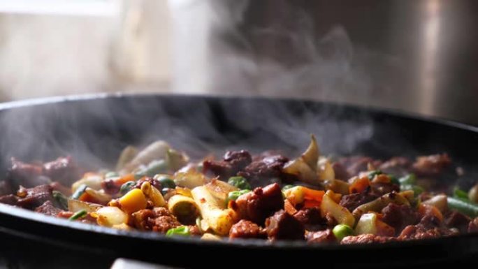 一块多汁的新鲜猪肉和蔬菜炖在煎锅上，用蒸汽特写。