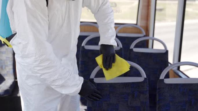 Hazmat团队工作人员在冠状病毒新型冠状病毒肺炎检疫上使用抗菌消毒湿巾对公交车内部进行消毒。戴防毒