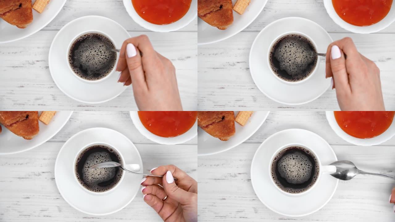 早餐时，女性手臂在瓷杯中混合热饮料。在4k红色相机上近距离拍摄