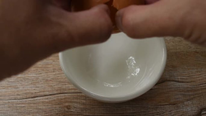 手工打开的蛋壳和生鸡蛋，蛋黄滴入