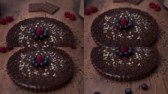 在木桌上摆着精美的现成巧克力蛋糕的特写镜头，上面装饰着水果和时令浆果，成分包括: 蓝莓，覆盆子，巧克