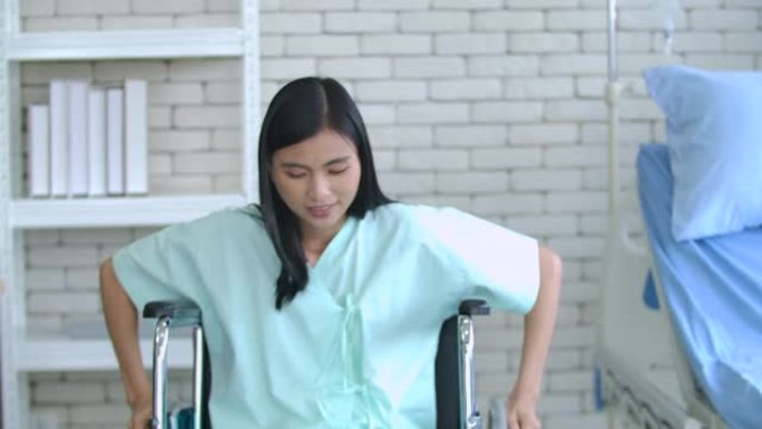 Covid 19位患者妇女坐在轮椅上，并在医疗中心或医院的窗户旁边的房间里移动轮椅。接到通知后，她高