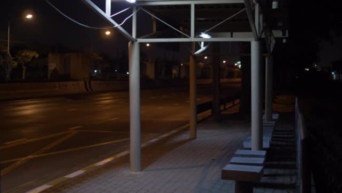 公交车站是空的，晚上城市的街道上没有人。