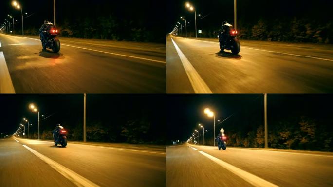 在小镇的夜间街道上骑着现代运动摩托车的人。摩托车手在夜城赛车。旅途中开车的人。自由和冒险的概念。后视