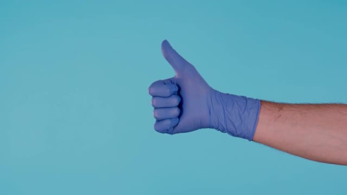 蓝色手术乳胶手套显示竖起大拇指的男性手孤立在蓝色背景