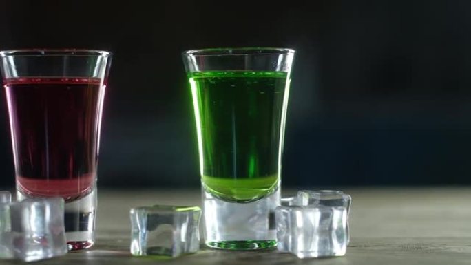 玻璃中红色和绿色酒精饮料的平移拍摄。