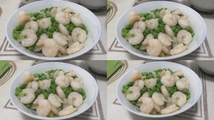 用白色中国碗煮熟的去皮虾和绿豌豆